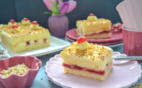 Stückchen eines Frankfurter Kranz Blechs mit Buttercreme, Kirschen und gehackten Nüssen.