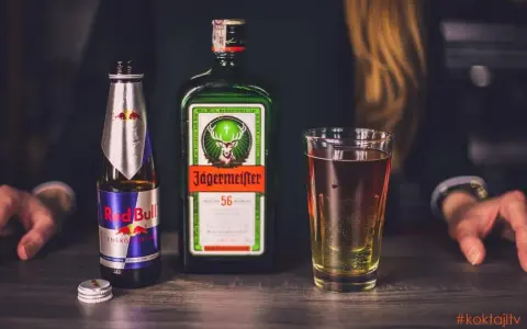 Butelka Jägermeister, puszka Red Bull i szklanka z drinkiem. Jägermeister to niemiecki likier ziołowy, często mieszany z napojami energetycznymi.