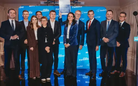 Grupa ludzi na scenie, wśród nich Janusz Sowa, odbiera dyplom. W tle niebieskie banery z logo Puls Farmacji.
