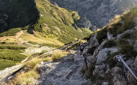 Turysta pokonuje kamienisty szlak z łańcuchami. Czy szlak na Giewont jest trudny? Ten odcinek wymaga ostrożności i dobrej kondycji.