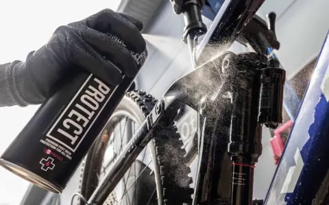 Rękawica z puszką "PROTECT" rozpyla środek na ramę roweru elektrycznego, pokazując, jak myć rower elektryczny.