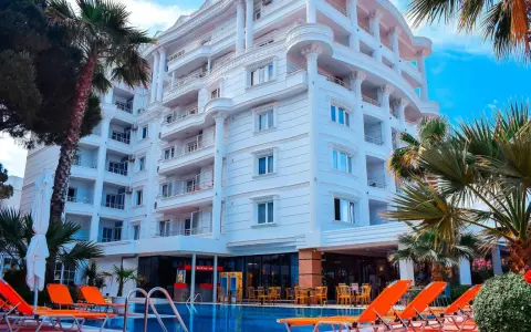 Biały hotel z balkonami i basenem, otoczony palmami. Idealne miejsce na fafa mel holiday.