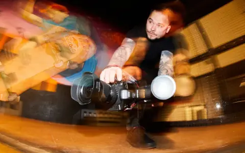 Fotograf z tatuażami łapie ruch deskorolkarza z Red Bulla. Krótki czas naświetlania uchwycił dynamiczną akcję.