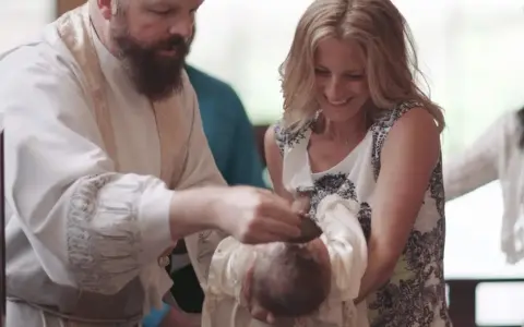 A priest performs a baptism, pouring water on a baby's head. The mother smiles, holding her child. This image captures the sacred moment of how to baptize someone.