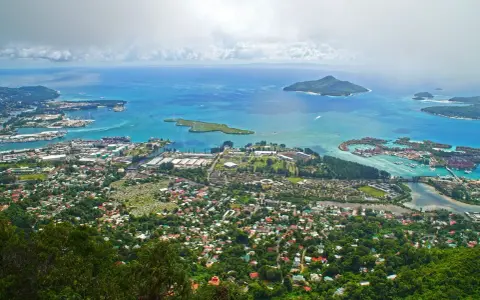 Widok z góry na wyspę z portem, domami i turkusowym morzem. Czy to Seszele, czy Mauritius?