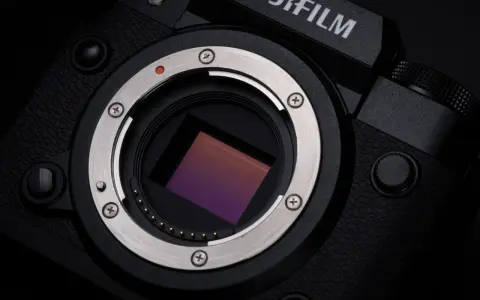 Zbliżenie na matrycę aparatu Fujifilm xh2s, lśniący metalowy pierścień mocowania obiektywu i czerwona kropka sygnalizująca montaż.