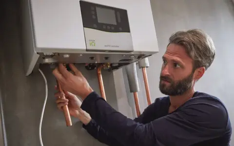 Installazione di una caldaia. Si sente il rumore dell'acqua che scorre mentre un tecnico collega i tubi di rame.