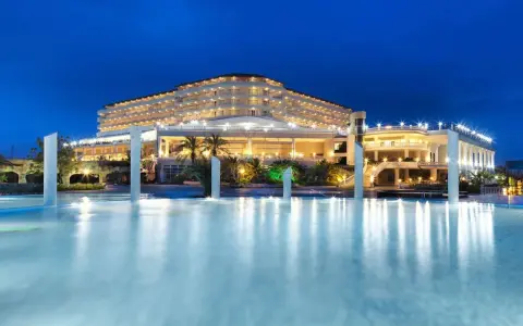 Elegancki Starlight Resort Hotel nocą, z oświetlonym basenem i palmami.