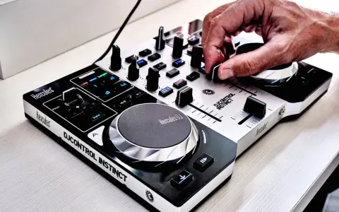 Dłoń DJ-a miksuje szybkie piosenki do tańca na kontrolerze Hercules DJControl Instinct.