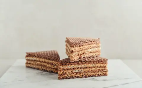 Słodkie wafle z kajmakiem, ułożone na marmurowym blacie, kuszą chrupiącą teksturą i kremowym nadzieniem.