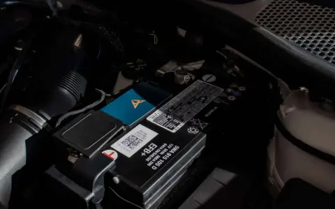 Akumulator w Audi Q7 znajduje się pod maską, obok filtra powietrza. Widoczny jest też niebieski gadżet z logo Cupra.
