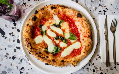 Pizza Margherita: darauf sind Tomatensauce, Mozzarella und frische Basilikumblätter.