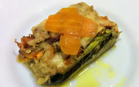 Deliciosa lasaña de verduras sin pasta, con capas de calabacín, zanahoria y queso fundido, servida en un plato blanco.