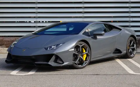 Szary Lamborghini Huracan z żółtymi zaciskami hamulcowymi na tle metalowej ściany.