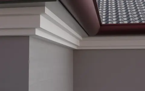 Elegancki gzyms zdobi narożnik budynku, harmonizując z dachówką i rynną.