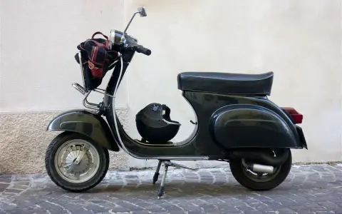 Moto d'epoca, un classico intramontabile. Dopo quanti anni mantiene ancora il suo fascino? Un casco e una borsa completano il look.