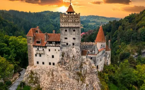 Majestatyczny zamek w Transylwanii, górujący nad lasami o zachodzie słońca.