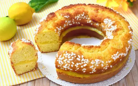 Un soffice ciambellone al limone, con una golosa crema gialla all'interno e decorato con perline di zucchero. Perfetto per la colazione o la merenda.