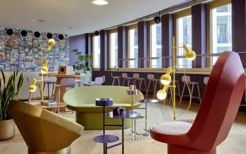 Ein bunter, moderner coworking space cologne mit auffälligen Möbeln, Comic-Wand und gelben Stehlampen.