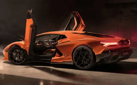 Pomarańczowy Lamborghini Revuelto z otwartymi drzwiami, ukazujący sportowe wnętrze i agresywną sylwetkę.