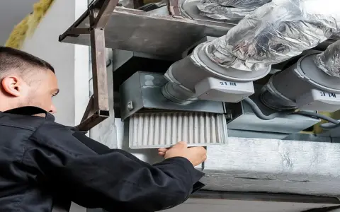 Un technicien retire un filtre encrassé d'un système de ventilation, signe que la vmc ne fonctionne plus correctement.