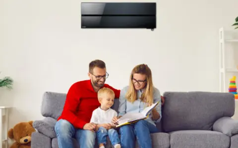 Familia feliz en el sofá, disfrutando de un momento tranquilo bajo el aire acondicionado de bajo consumo.