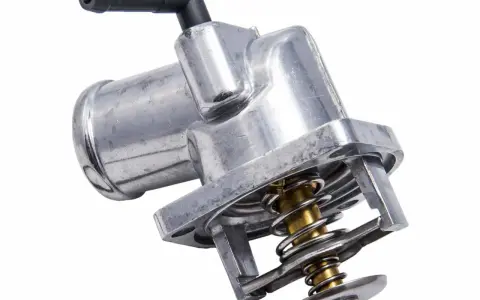 Metalowy termostat w samochodzie z widoczną sprężyną i zaworem. Kluczowy element układu chłodzenia.