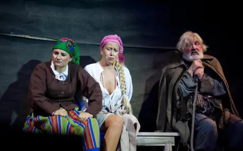 Trzech aktorów w strojach ludowych na scenie Teatru Muzycznego Gdynia.