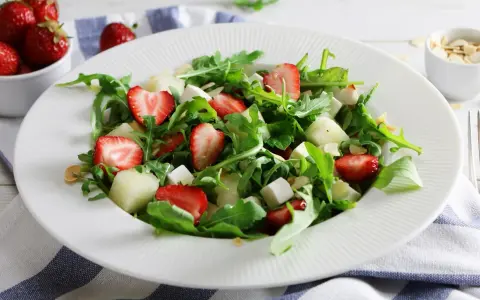 Orzeźwiająca sałatka z rukolą, truskawkami, melonem i serem feta. Posypana płatkami migdałów.