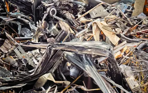 Góra złomu, poskręcane metalowe elementy, tworzące chaotyczną strukturę. Widoczne fragmenty blachy, prętów i innych odpadów. Kod odpadu: 17 04 05.