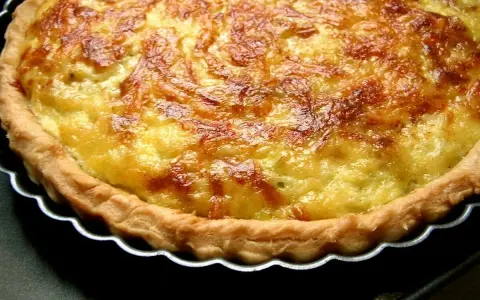 Une tarte aux poireaux dorée et appétissante, prête à être dégustée. Sa croûte croustillante et sa garniture onctueuse invitent au partage.