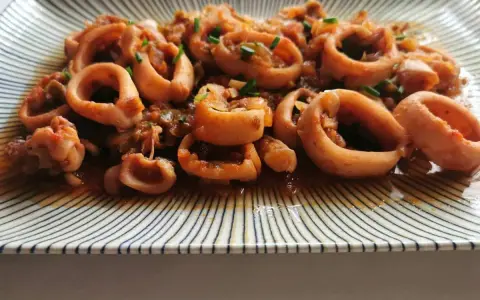 Calamares a la riojana, un plato tradicional español con aros de calamar cocinados en una sabrosa salsa de tomate y pimientos.