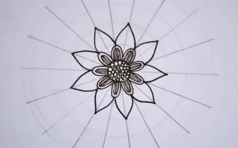 Kwiatowa mandala, rysowana czarnym tuszem, z delikatnymi okręgami i promieniami.