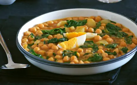 Un plato humeante de garbanzos con espinacas y huevo duro, una de las muchas deliciosas recetas con garbanzos.