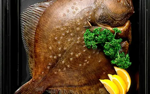 Hel, helgrillad piggvar i ugn, garnerad med persilja och citronklyftor.