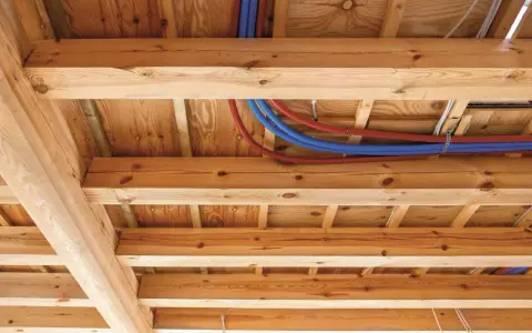 Drewniane belki stropowe z widocznymi instalacjami hydraulicznymi i elektrycznymi.