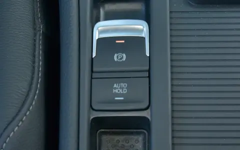Przycisk AUTO HOLD w samochodzie. To funkcja, która automatycznie utrzymuje pojazd w miejscu po zatrzymaniu.