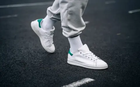 Un paio di sneakers bianche con dettagli verdi, simbolo di stile e comfort. Il loro significato va oltre la moda, rappresentando libertà di movimento.