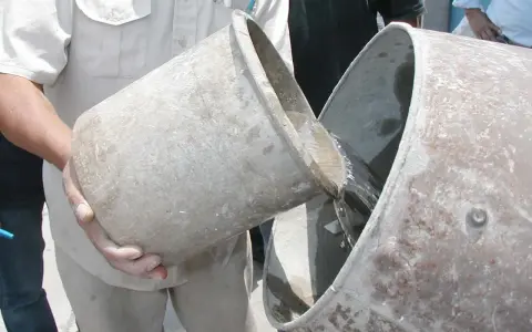 Se vierte agua de un cubo a otro, preparándose para proporcionar cemento y agua.