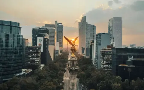 Goldene Viktoria-Statue im Sonnenuntergang, umgeben von modernen Wolkenkratzern in Mexico City.