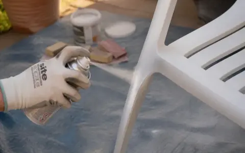 Application d'un apprêt sur une chaise blanche. Le temps de séchage de l'acétone avant peinture est crucial pour une finition parfaite.