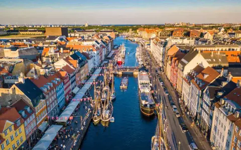 Navigazione nel porto di Copenaghen, con case colorate, barche a vela e un vivace lungomare.
