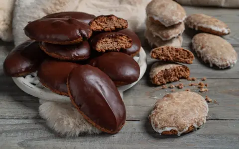 Biscotti tipici calabresi, alcuni ricoperti di cioccolato fondente, altri glassati, su un tavolo di legno.