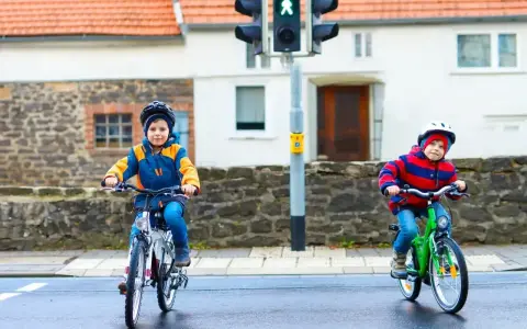 Dwóch chłopców na rowerach czeka na zielone światło. Czy karta rowerowa jest obowiązkowa? Bezpieczeństwo przede wszystkim!