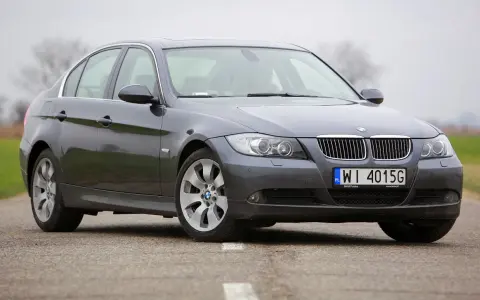 Szary sedan BMW e90 przedlift na drodze. Klasyczna linia nadwozia i charakterystyczne "nerki" na grillu.