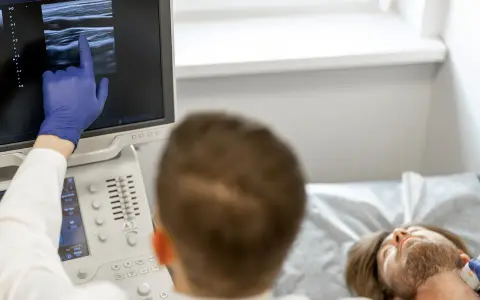 Lekarz wykonuje badanie doppler tętnic mózgowych, analizując obraz na monitorze USG.