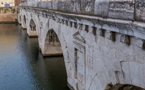 Il Ponte di Tiberio a Rimini, con i suoi archi in pietra bianca che si specchiano sull'acqua scura, testimonia secoli di storia.