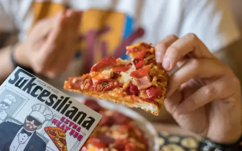 Kawałek pysznej pizzy od Kizo, z dodatkami mięsnymi i papryką, na opakowaniu widnieje napis "Sukcesiliana Extra Meat BBQ".