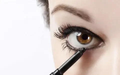 Ojo marrón recibiendo el toque final de maquillaje ojos negro con un lápiz.
