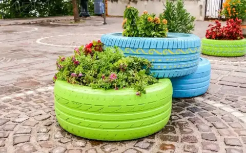 Kolorowe opony tworzą oryginalny skalniak z opon jak zrobic. W nich kwitną kwiaty, dodając uroku.